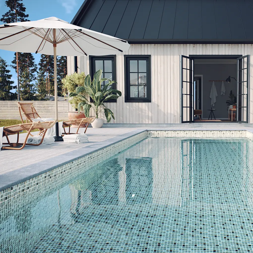En kund som byggt sin pool med Thermoblock, sandfärgad mosaikliner som ramas in av ett fint vitmålat hus
