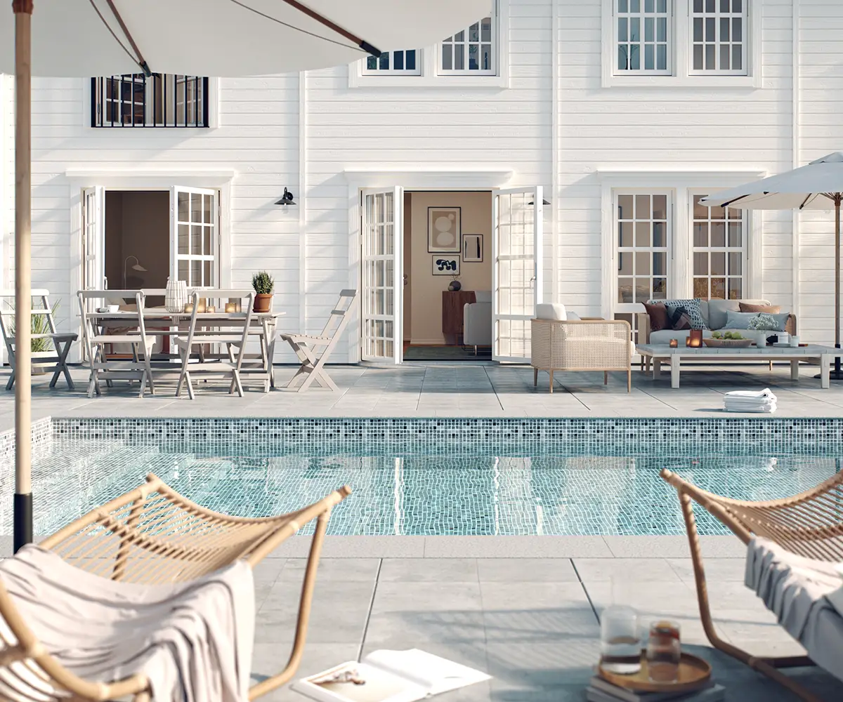 Två solstolar framför en pool med liner och kantsten framför ett vitt funkishus