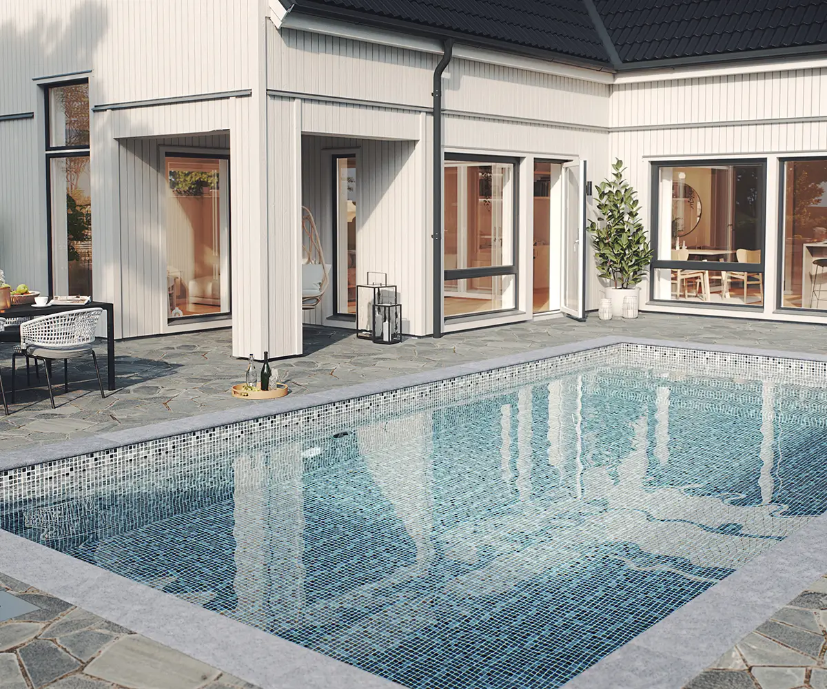 I anslutning till en vitmålad 1,5-plansvilla ligger en pool nedsänkt i altanen